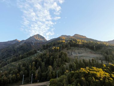 Mavi gökyüzünün arka planında gün batımında dağların panoramik manzarası. Dağlarda güzel gün batımı manzarası