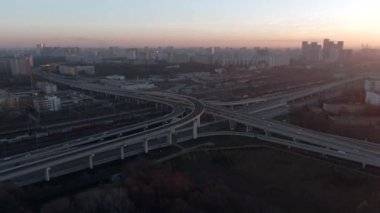 Gün doğumunda büyük şehrin merkezinde çok katlı ulaşım kavşağının hava manzarası. Modern şehrin güzel panoramik peyzaj altyapısı çok yükseklerden