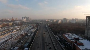 Şafak vakti, büyük bir şehirde, yüksek hızlı bir otoyol üzerinde hava manzaralı uçuş. Şehrin sokaklarında arabaların hareketi