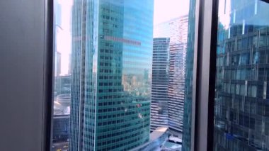 Ofiste, pencerenin dışında güzel bir manzarası olan bir yer. Camdan ve betondan yapılmış modern yüksek binalar..