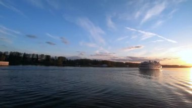 Gün batımında nehir boyunca yatı geçmek. Gün batımında mavi gökyüzünün arka planına karşı nehrin güzel renkli manzarası. Nehirde gemiyle seyahat etmek.