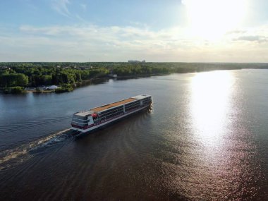 Hava manzaralı yolcu gemisi gün batımında güneşle buluşmak için yelken açar. Geminin güzel manzarası. Suyun üzerindeki güneşin yansıması.