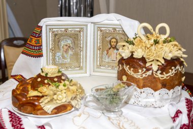 Düğün ekmeğindeki geleneksel Ukrayna simgeleri nakış havlusuna işlenmiş. Geleneksel Ukrayna düğün ekmeği ve işlemeli havluyla İsa ve Bakire İkonası.