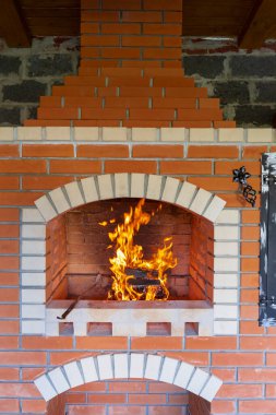 Ateş, barbekü, ızgara ve diğer açık hava yemekleri için bir yaz tuğlası fırınında yakılıyor. Pizza fırını ve ızgara ızgarası olan açık hava yaz mutfağı. Açık havada Brick BBQ Izgarası ve Fırın.