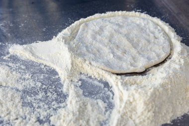İtalyan orijinal pizza hamuru. Masada un ve pizza hamuru var..