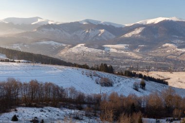 Kışın gün batımı Karpatya dağlarında. Güneş diski ve uzun ışınlar kış dağlarında gün batımında. Dağlarda resim gibi bir gün batımı. Canlı bir duvar kağıdı..