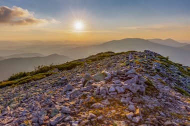 Karpat dağlarında, Gorgan bölgesinin kayalık çıkıntıları üzerinde büyülü bir yaz günbatımı. Dağlarda, dağın kayalık yüzeyinde gün batımını canlandırın. Canlı fotoğraf duvar kağıtları