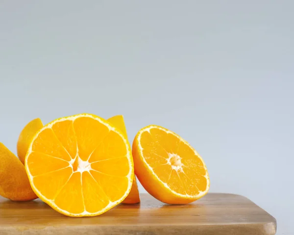 ぼやけた灰色の背景の上のまな板上のオレンジの部分 — ストック写真