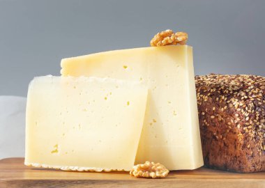 Mutfak tahtasının üzerinde Asya peyniri, ceviz ve ekmek parçaları.