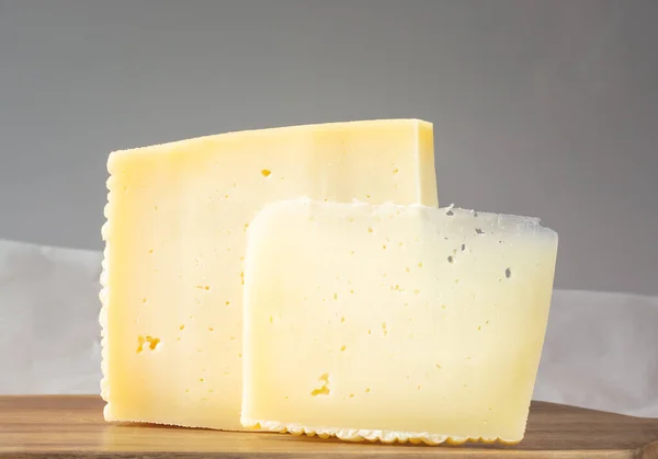 Dos rebanadas de queso asiago sobre un fondo gris — Foto de Stock