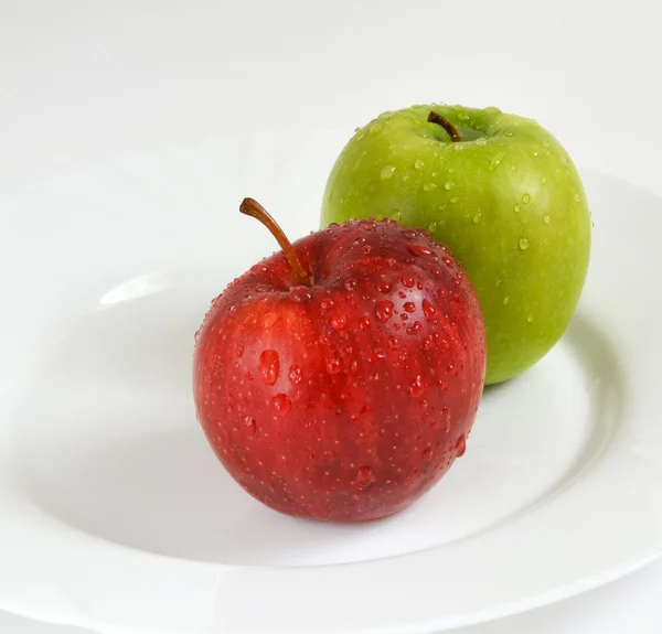 Deux pommes sur une assiette blanche — Photo