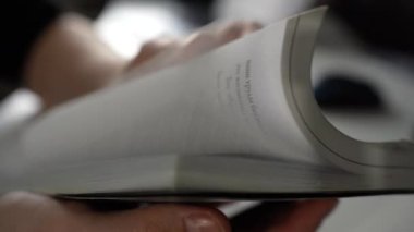 İş yerinde dizüstü bilgisayarla bir kitabın sayfalarını çeviren ellerin yakın plan görüntüsü