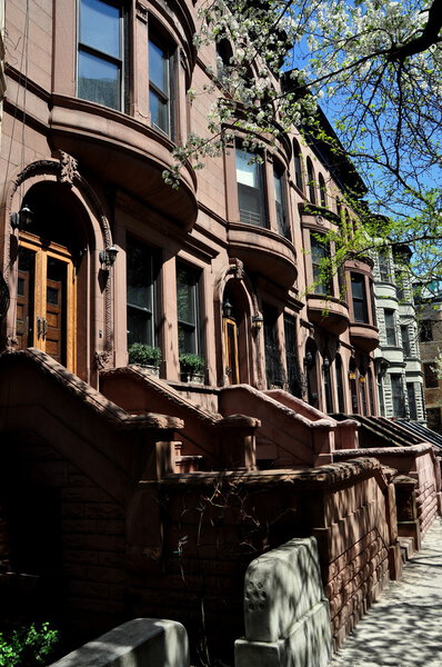 New York City - May 2, 2015: A row of early 20th century brownstones with high stoops on West 143rd Street between Amsterdam and Convent Avenues in Hamilton Heights