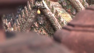 Mozaikli eski bir Tayland tapınağının duvarlarında rüzgarda sallanan altın çanlar. Şafağın tapınağı. Yakın plan. Odaklanma değişimi