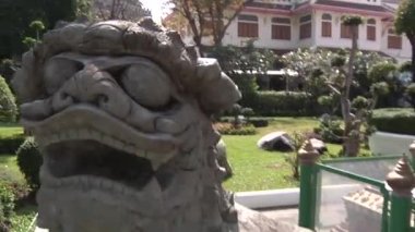 Korkunç hayvan heykelleri ve Bangkok 'taki Wat Arun Thai tapınağında asası olan bir adam. 