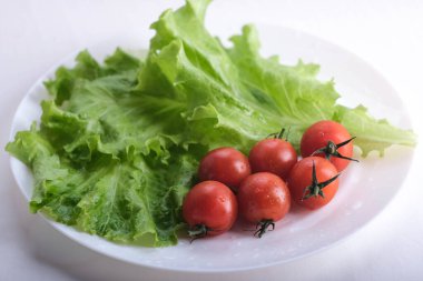 Kiraz domatesli yeşil marul. Vitaminler beyaz tabakta..