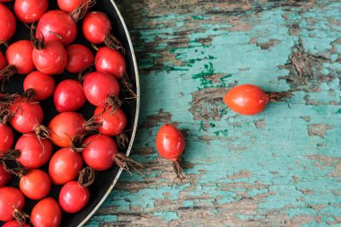 Koyu bir tabakta olgun, büyük bir gül kalçası. Toplanan gül kalçalar bir kasenin içinde. Rosehip tıbbi amaçlı. Gül çayı..