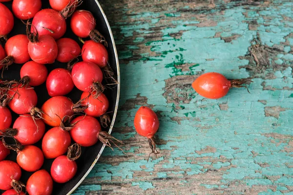 Koyu bir tabakta olgun, büyük bir gül kalçası. Toplanan gül kalçalar bir kasenin içinde. Rosehip tıbbi amaçlı. Gül çayı..