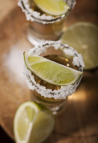 Tiros de tequila de oro con frutas de lima — Foto de Stock