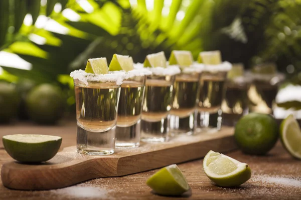 Gold tequila shots with lime fruits — Stock Photo, Image