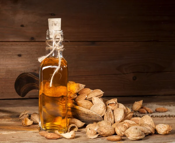 Almond oil on an old wooden background — Stock Photo, Image