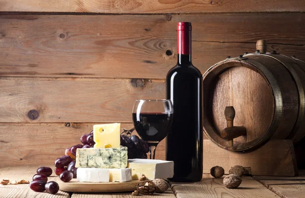 Vino tinto con varios tipos de queso sobre fondo de madera — Foto de Stock