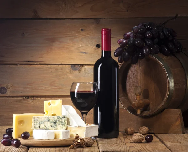 Vin rouge avec différents types de fromage sur fond en bois — Photo