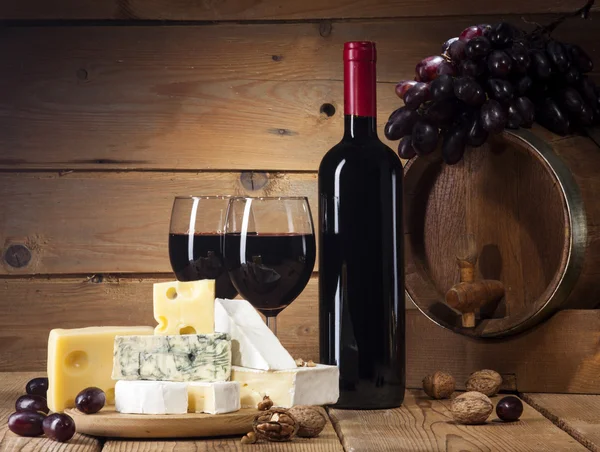 Vin rouge avec différents types de fromage sur fond en bois — Photo