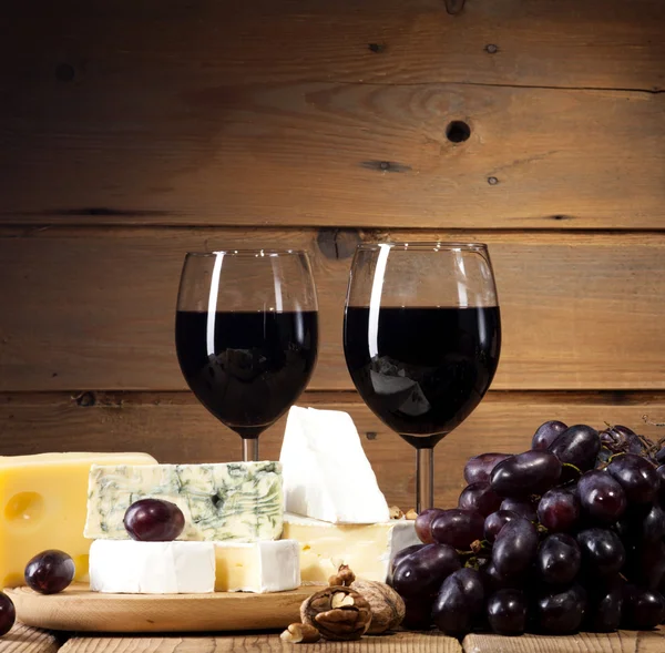 Vin rouge avec différents types de fromage sur fond en bois — Photo