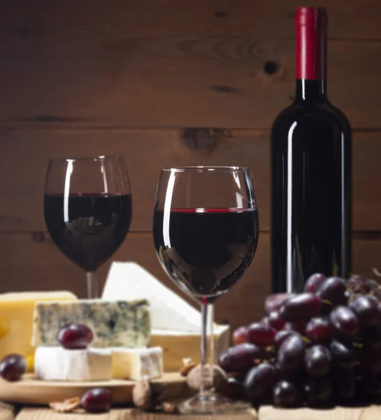 Rotwein mit verschiedenen Käsesorten auf Holzgrund — Stockfoto