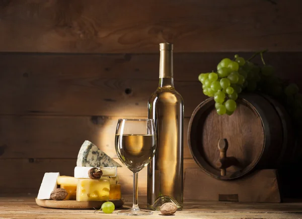 Vinho branco com vários tipos de queijo em fundo de madeira — Fotografia de Stock