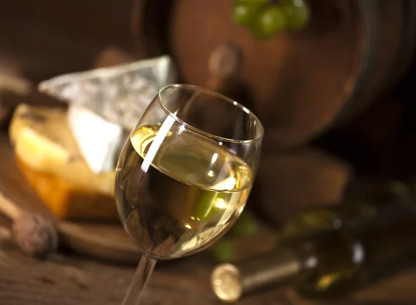 Vinho branco com vários tipos de queijo em fundo de madeira — Fotografia de Stock