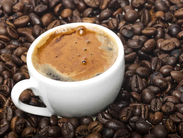 Kahve çekirdekleri zemin üzerine beyaz fincan — Stok fotoğraf