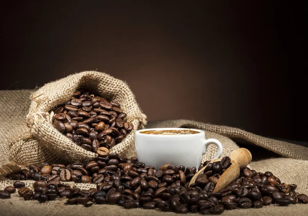 Taza blanca con granos de café sobre fondo oscuro — Foto de Stock