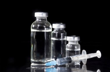 Cam ilaç şişeleri ve siyah arka plan üzerine şırınga