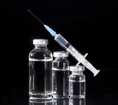 Cam ilaç şişeleri ve siyah arka plan üzerine şırınga