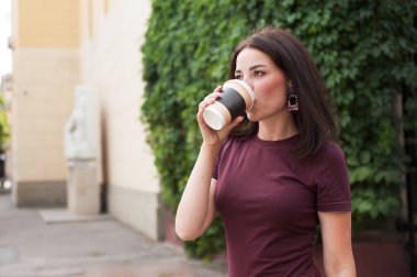 Güzel esmer yazın sokakta kahve içiyor.