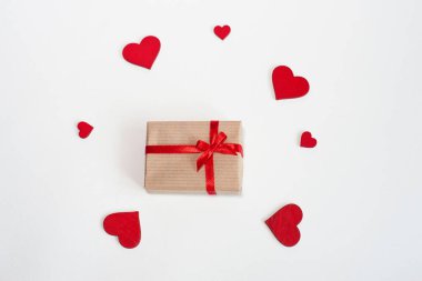 Kırmızı kurdeleli, arka planda kalpleri olan bir hediye. Üst görünüm