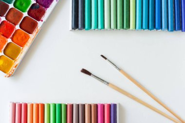 Beyaz arka planda boya fırçaları ve pasteller