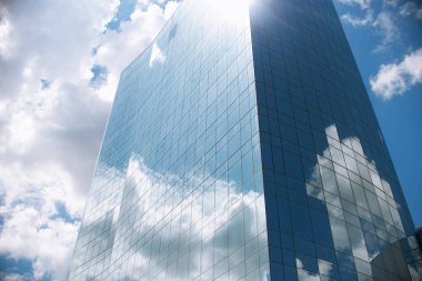 a building with a mirrored facade against a blue sky on a sunny day