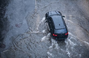 Kyiv, Ukrayna - 15 Haziran 2020: BMW X5 arabasının altında su birikintisi. Sağanak yağmurda siyah araba sürüyor.