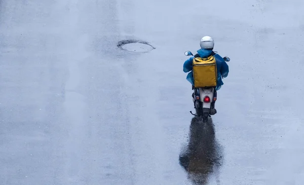 Voedsel Bezorger Een Blauwe Regenjas Met Een Gele Doos Zijn Stockfoto