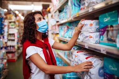 Genç bir kadın, koronavirüs salgını karantinası sırasında steril maske takarak bir süpermarkette dezenfekte ve temizlik temizliği yapıyor. Sağlık ve ev temizleme konsepti