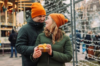 Hediye kutusu olan bir çift. Adam sokakta kız arkadaşına sarı kurdeleli küçük bir hediye veriyor. Kadın erkek arkadaşından hediye alır. Sevgililer Günü ve Noel konsepti