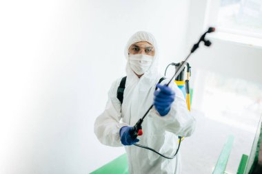 Koruyucu kıyafet giymiş, merdivenlerin girişindeki apartmanları dezenfekte eden profesyonel bir işçiyi yakından çek. Yaşam alanlarında koronavirüs önleme. Yeni normal ve Covid-19 yayılmasını durdur