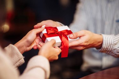 Sevgililer Günü konsepti. Bir kafede birbirlerine hediyeler verirken kadın ve erkeğin yakın çekimleri. Restoranda kutlama yapan genç bir çift. Yeni normal, kış tatili