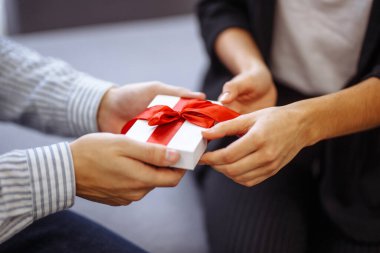 Ellerinde kırmızı kurdele olan beyaz hediye kutusu. Aşık mutlu bir çift. Sevgililer Günü 'nü kutlayan genç bir çift. Çiftler birbirlerine hediye verirler. Sevgililer Günü konsepti