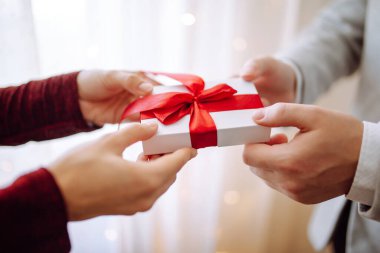 Sevgililer Günü konsepti. Elinde kırmızı kurdele olan bir hediye kutusu. Sevgili çift 14 Şubat 'ta birbirlerine hediyeler verir. Romantik erkek arkadaş ve kız arkadaş sevgililer gününü kutluyor.