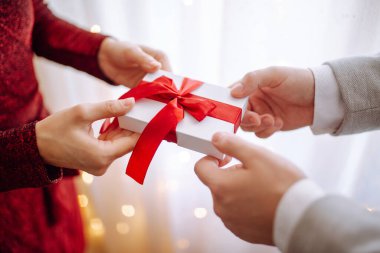 Sevgililer Günü konsepti. Elinde kırmızı kurdele olan bir hediye kutusu. Sevgili çift 14 Şubat 'ta birbirlerine hediyeler verir. Romantik erkek arkadaş ve kız arkadaş sevgililer gününü kutluyor.