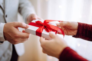 Sevgililer Günü konsepti. Elinde kırmızı kurdele olan bir hediye kutusu. Sevgili çift 14 Şubat 'ta birbirlerine hediyeler verir. Romantik erkek arkadaş ve kız arkadaş sevgililer gününü kutluyor.